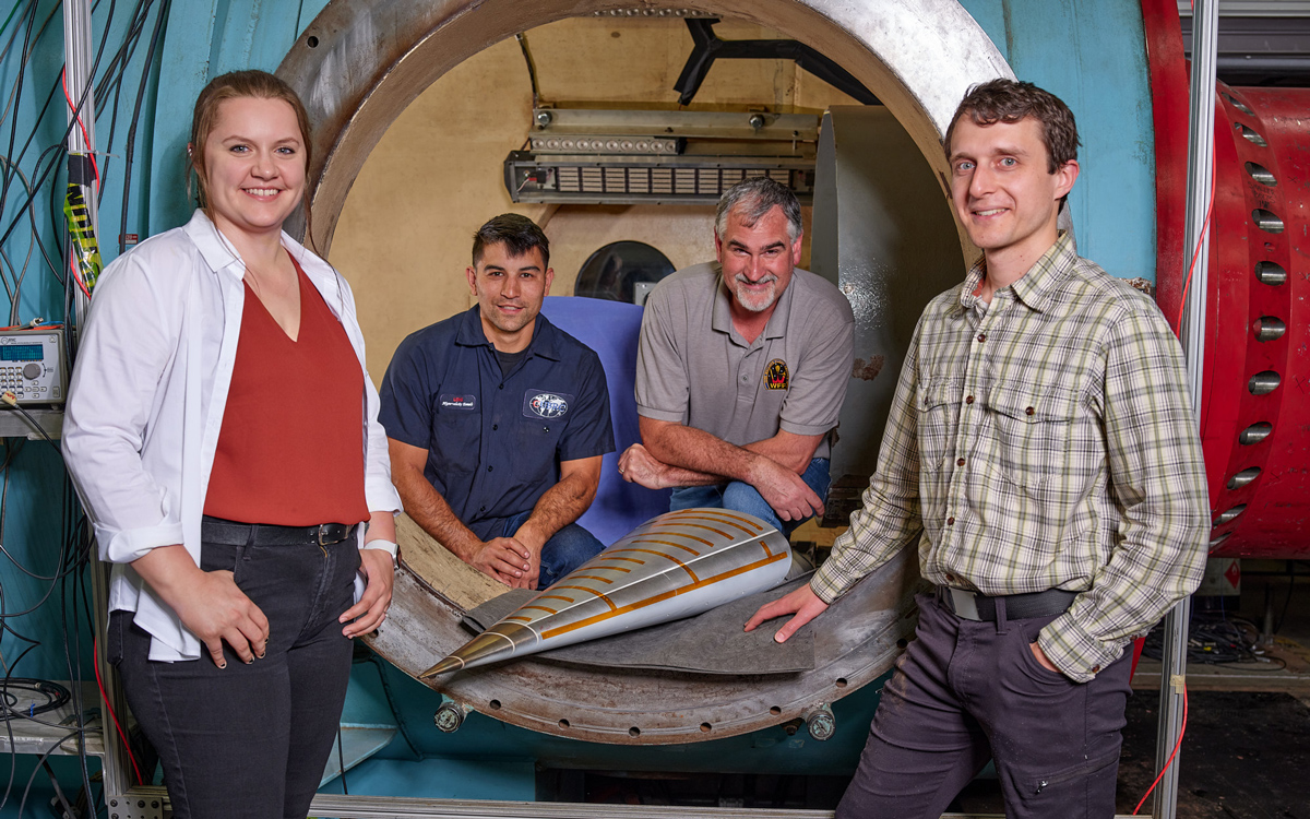 cubrc employees stand around model in test facility